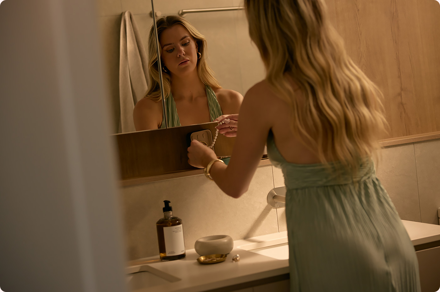 Image: Woman Putting On Jewellery In Bathroom